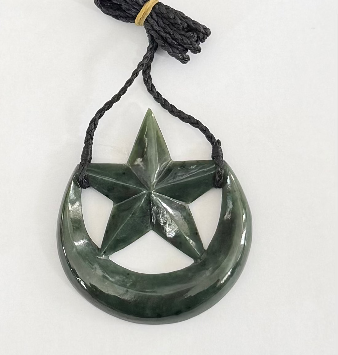 Greenstone pendant with star design on a white background