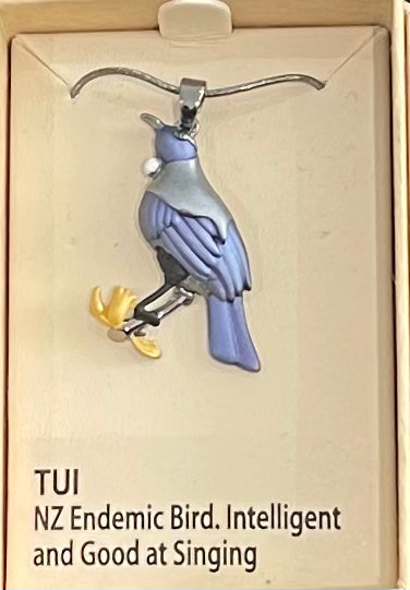 Bird-shaped pendant with 'TUI' information on a beige background