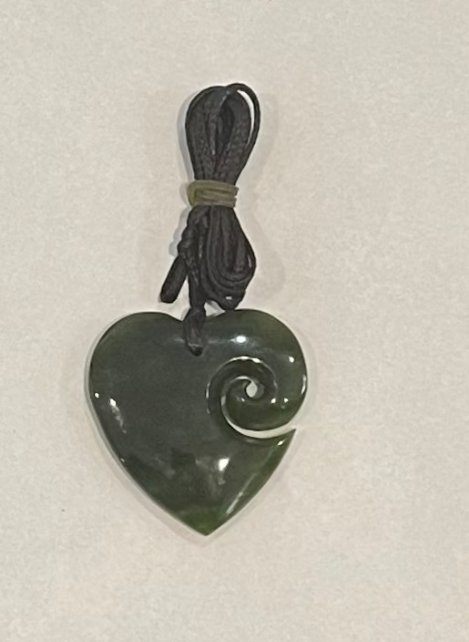 Heart-shaped Pounamu jade pendant with spiral design on a white background