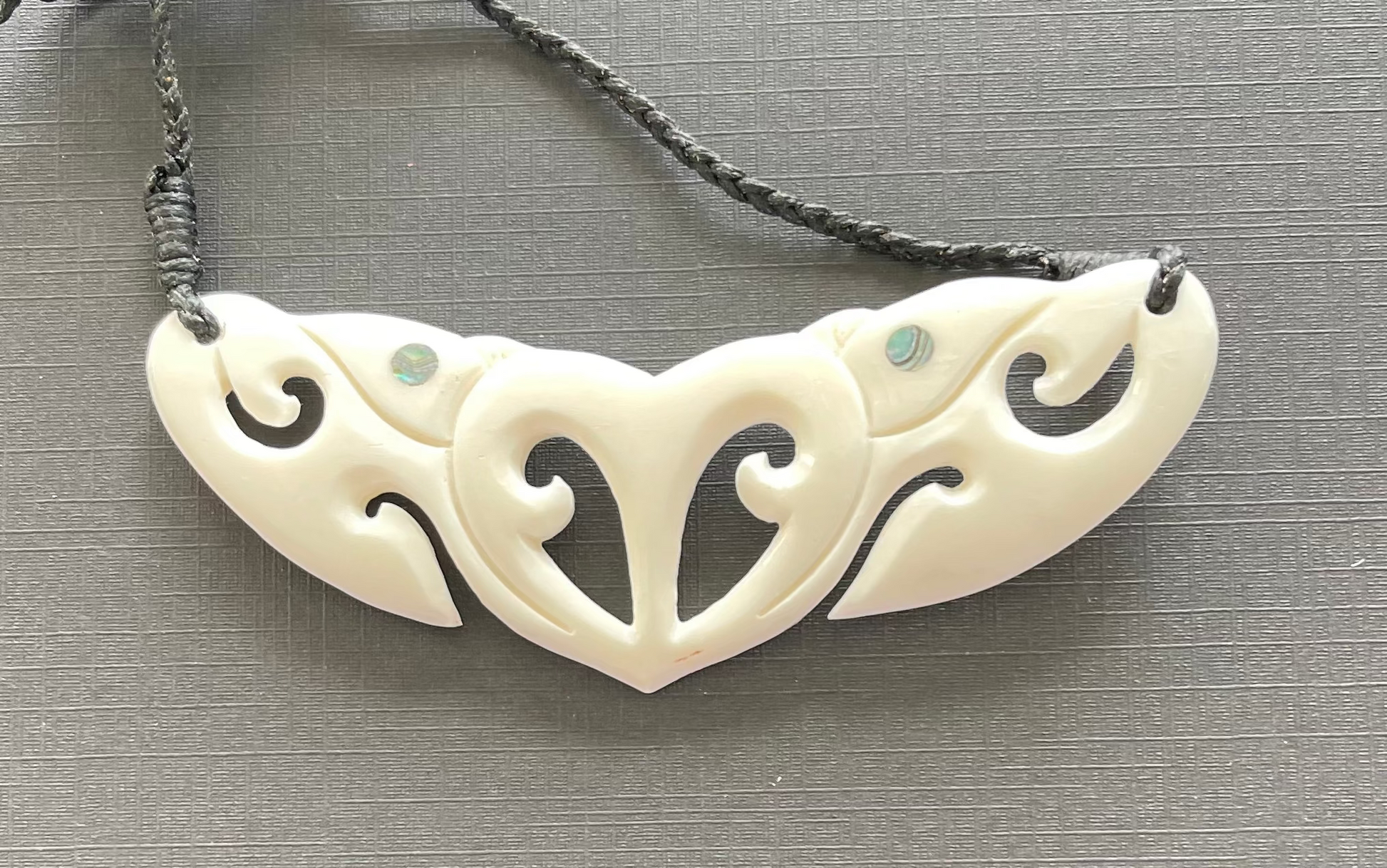 White bone necklace with intricate carvings on a gray background