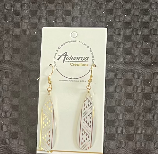 Gold earrings on a branded card against a textured gray background