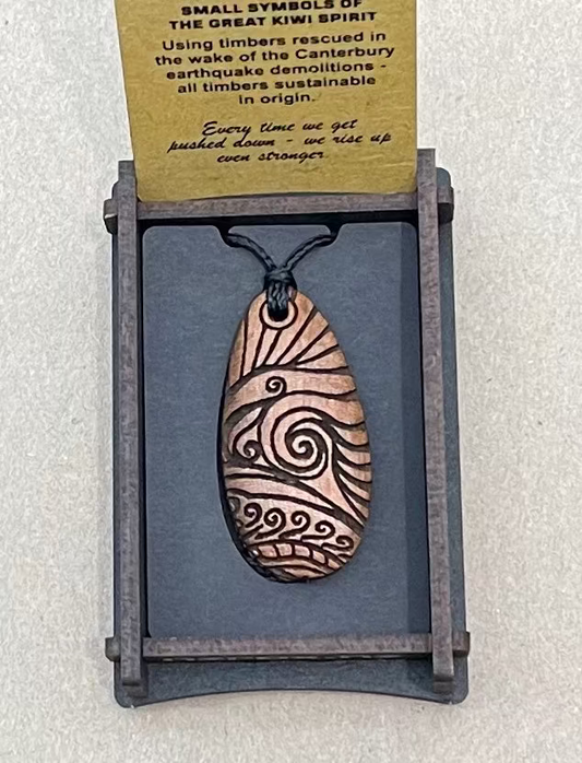 Wooden pendant with wave design on a gray card with text