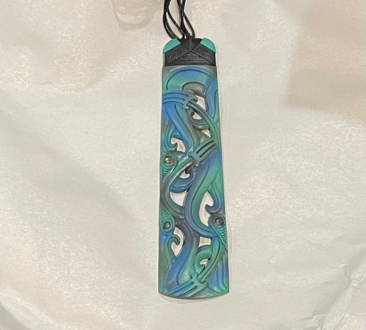 Colorful bone carving pendant with intricate design on a white fabric background
