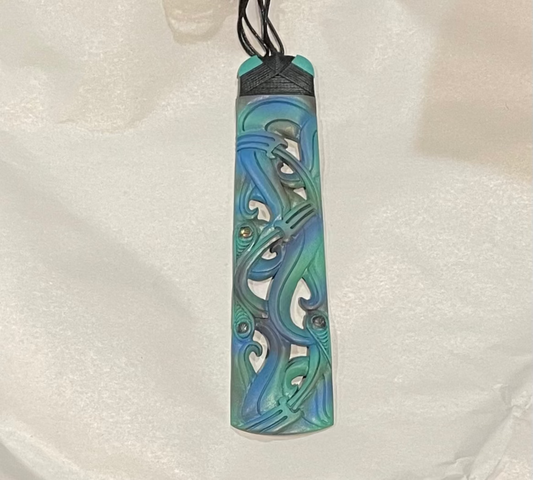 Colorful bone carving pendant with intricate design on a white fabric background