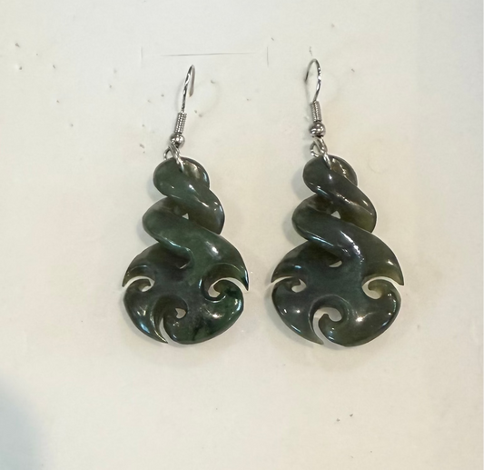 A pair of dark green carved stone earrings with silver-tone fishhook wires, displayed against a plain off-white background.