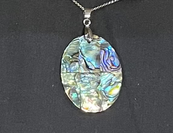 Paua shell pendant on a black background