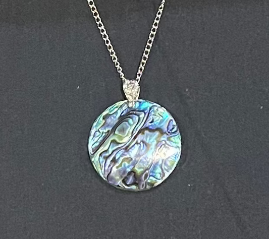Paua Necklace with a round, multicolored pendant on a dark background