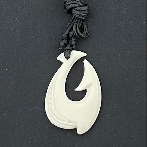 White fish hook pendant on a black background