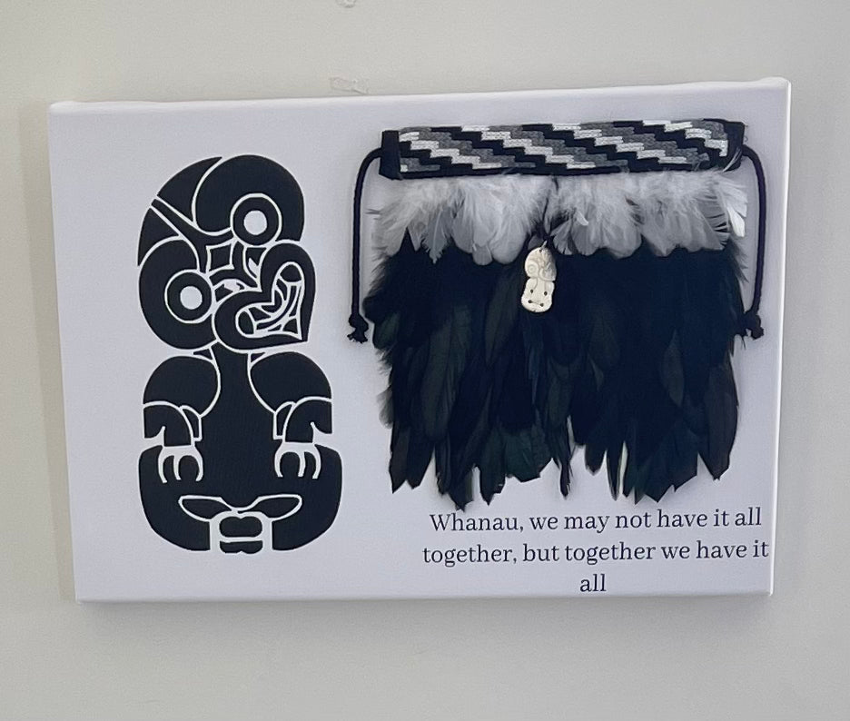 Korowai with a decorative box featuring a Maori Tiki and text.