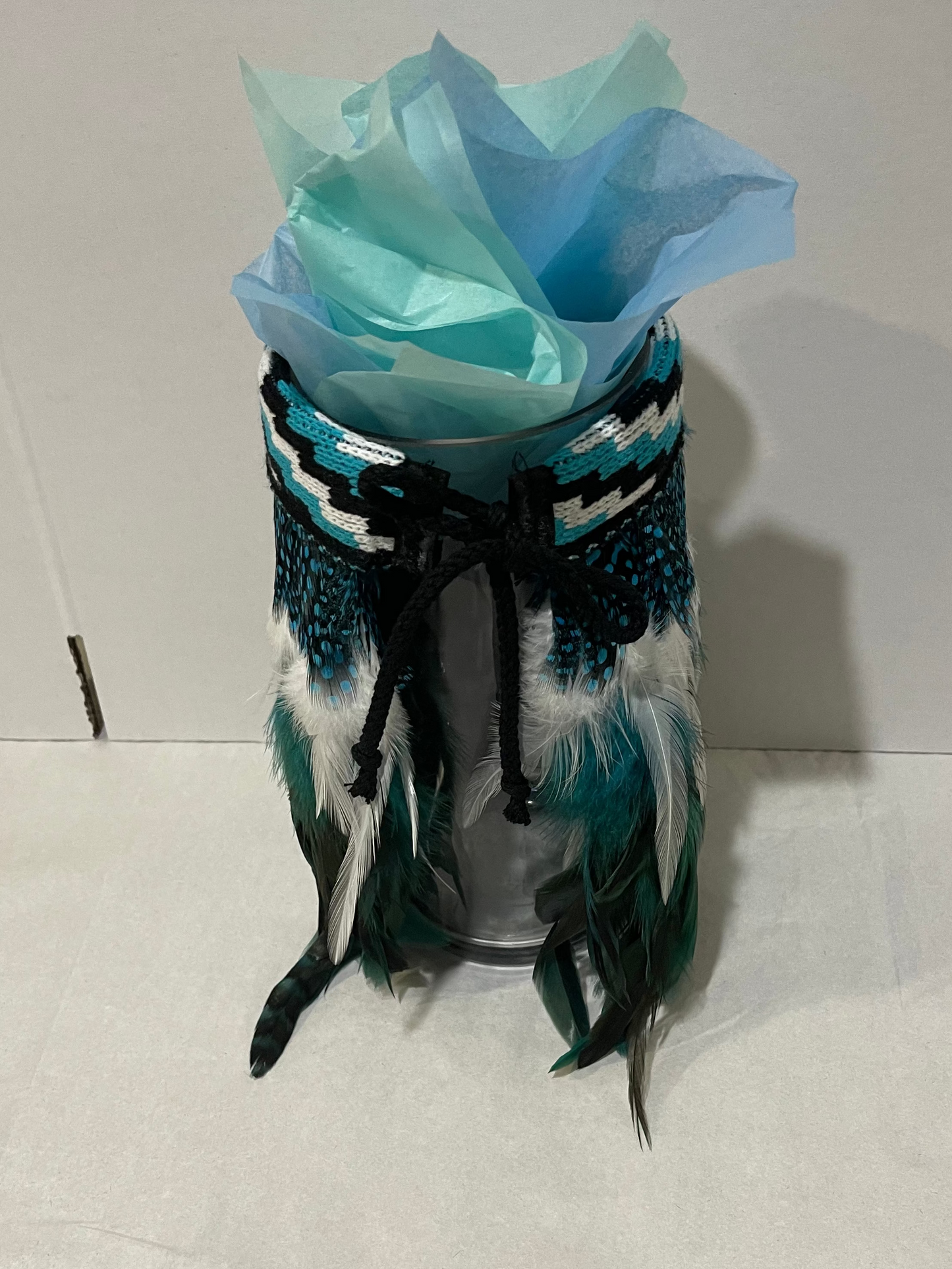 Decorative vase with a mini Maori Korowai and tissue paper on a white surface